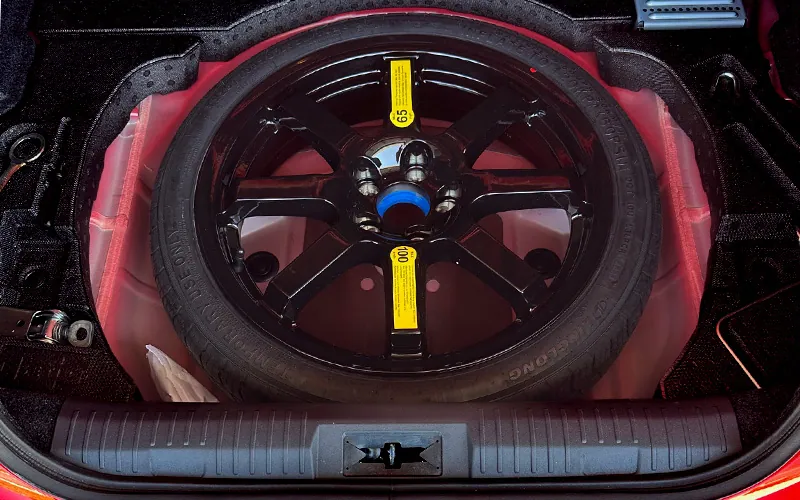 Spare tire neatly stored in the trunk of a Subaru BRZ with black alloy wheel